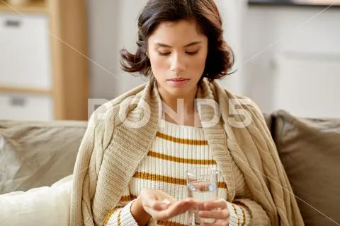 Sick woman taking medicine with water at home Stock Photos