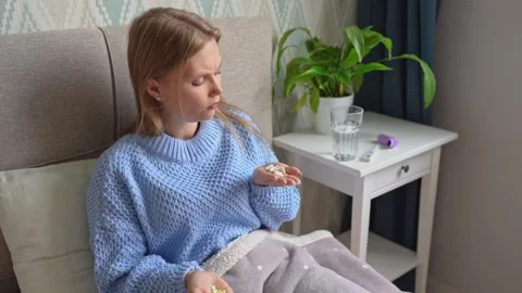 Sick woman with two different types of pills in her hands on bed at home. Stock Footage 138816759