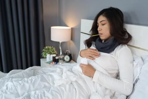 Sick woman using thermometer to checking her temperature and her headache in  Foto stock