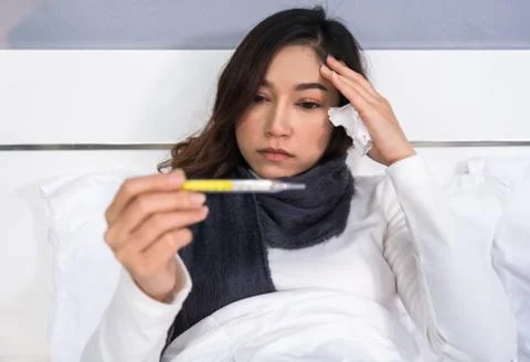 Sick woman using thermometer to checking her temperature and her headache in  Fotos de archivo