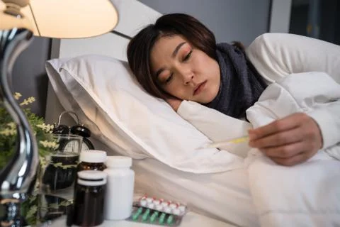 Sick woman using thermometer to checking her temperature and her headache in  Stock Photos