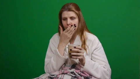 Sick woman wrapped in warm blanket drinking hot tea. Cough. COVID Danger of Video stock 127913853