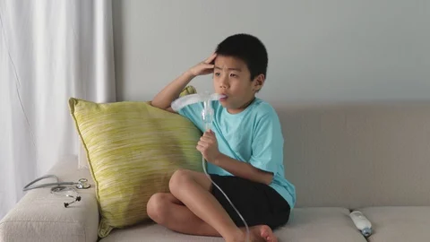 Sick young asian boy using nebulizer medication at home. Asthma, coronavirus flu Stock Footage 127995095