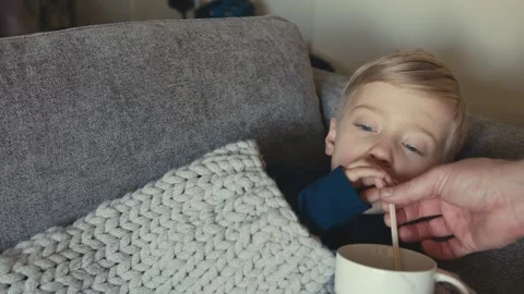 Sick young boy drinking hot tea on the sofa Stock-Footage 347099684