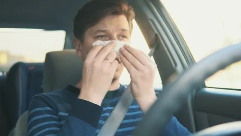 A sick young man is blowing his nose in the car Stock Footage 87349213