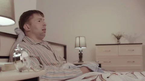 Sick young man lying in bed and sneezing Видео 68420945