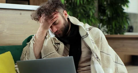 Sick young man using laptop coughing at home. Working remotely at home. Concept Видео 168475246