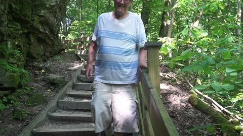 Sickly Elderly Man in the woods  slowly walking down a set of wooden stairs Video stock 111424950
