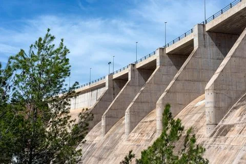 Side and bottom view of a dry concrete river dam with trees next to it Stock Photos