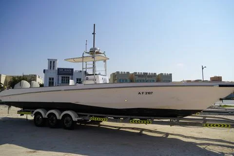 Side and close up view of a white speedboat is parked on a cart by the beach. Фото