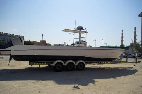 Side and close up view of a white speedboat is parked on a cart by the beach. Fotos de archivo