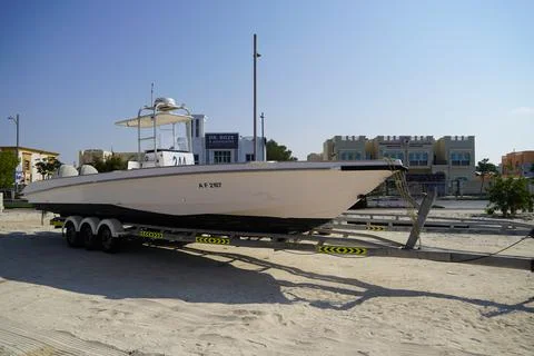 Side and close up view of a white speedboat is parked on a cart by the beach. Stockfoto's
