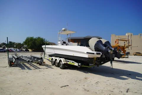 Side and close up view of a white speedboat is parked on a cart by the beach. Stock Photos
