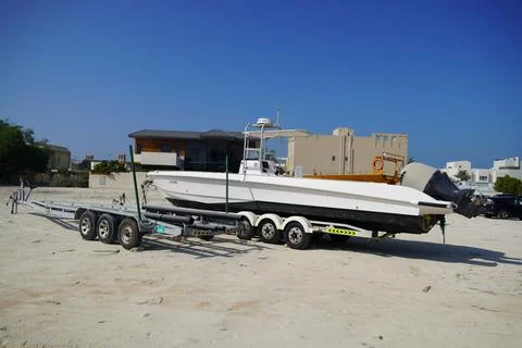 Side and close up view of a white speedboat is parked on a cart by the beach. Stock Photos
