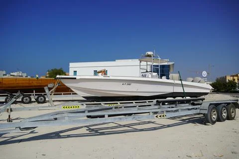Side and close up view of a white speedboat is parked on a cart by the beach. Stock Photos