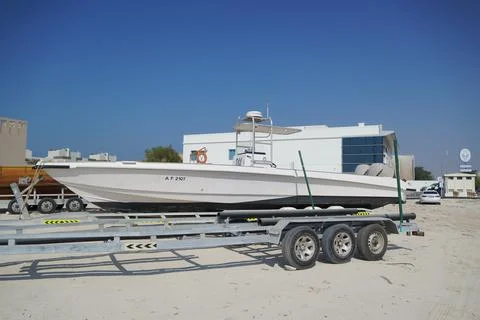 Side and close up view of a white speedboat is parked on a cart by the beach. Fotos de archivo