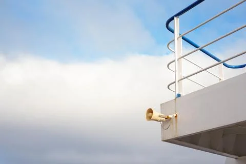 Side-Angle Close-Up of a Ship Horn on a Grey Deck with Blue and White Railing, U Stockfoto's