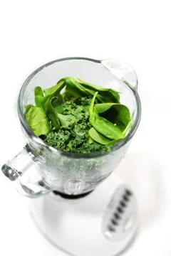 Side Angle of Green Leafy Kale &amp; Spinach in Glass of Blender Stock Photos