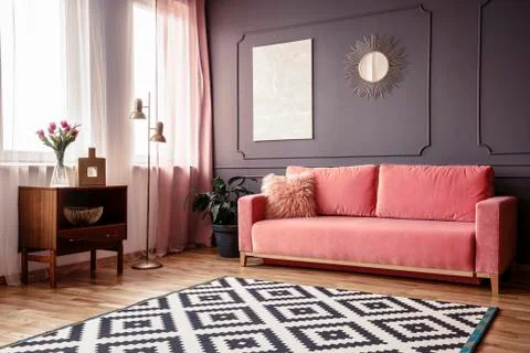 Side angle of a living room interior with a powder pink sofa, patterned rug,  Foto stock
