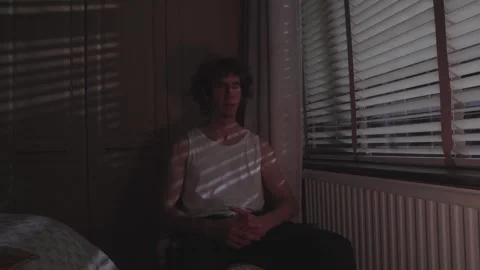 Side Angle of Man Leaning Forward in Deep Thought in Dim Room Stock Footage 308641583