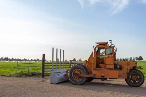 Side angle of orange tractor with a plow in a field with blue sky Stock-Fotos