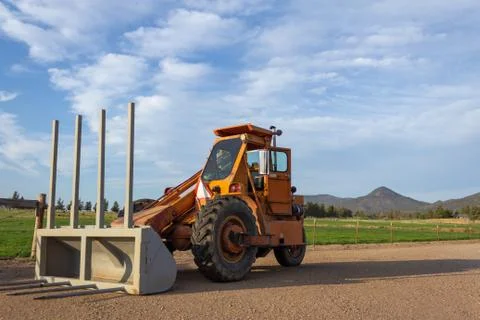 Side angle of orange tractor with a plow in a field against blue sky Fotos Stock