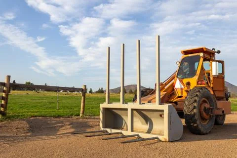 Side angle of orange tractor with a plow in a field with blue sky Stock Photos
