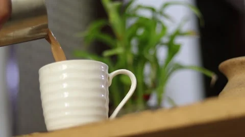 Side angle of pouring refreshing Indian tea in a cup. Early morning masala chai Stock Footage 245096309
