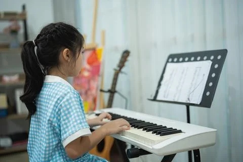 Side Angle Profile of Focused Cute Little Asian Girl Playing Electric Keybo.. Stock Photos