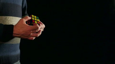 Side angle shot of a man solving a Rubik´s cube isolated on a black background Stock Footage 60672143