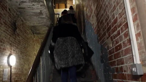 Side angle shot of people walking up the stairs in old building 스톡 동영상 107617906