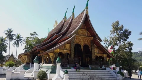 Side angle shot of Wat Xieng Thong temple entrance on a sunny day, visitors Video stock 81740294