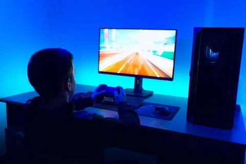 Side angle view of boy holding game controller while playing racing video g.. Stock Photos