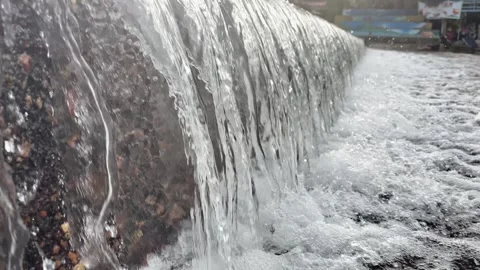 Side angle view of clear water spilling over a concrete weir wall Stock Footage 346012667
