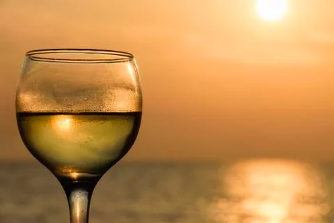 Side Angle View Of Glass Filled With White Wine Against Sea At Sunset Stock Photos