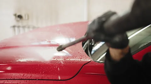 Side angle view of a man worker cleaning modern red automobile with high Stock Footage 234017533