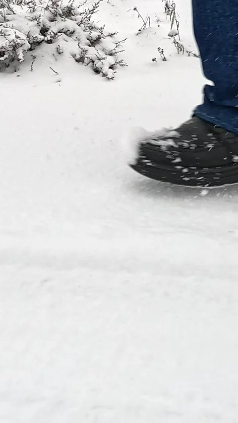 Side-angle winter walking steps on snowy ground with slow forward motion Stock Footage 322092549