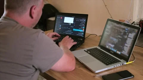 Side back view man working on two laptops typing program code on keyboard Stock Footage 243583913