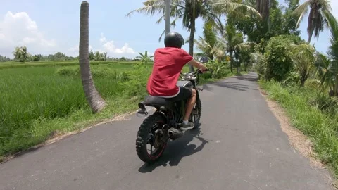 Side back view of young man riding on a black custom bike among of the road surr Stock Footage 130838896