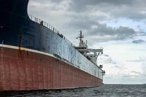 Side of a cargo ship viewed from the sea on a slightly cloudy day Stock Photos