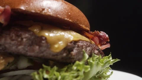 Side Close Up Of A Burger Rotating on a Plate Display Against Black Background Stock-Footage 131028092