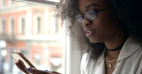 Side close-up portrait of the surprised afro-american woman with glasses holding Stock Footage 83369254