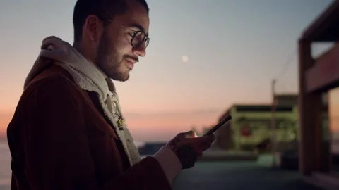 Side close up portrait of trendy young handsome guy holding black smartphone Stock Footage 136673984