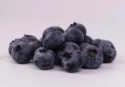 Side close view of a group of black fresh blueberries on white background Stock Photos