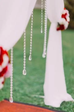 The side close-up view of the hanging beads on the wedding arch with flowers. Stock Photos