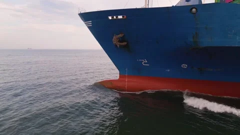 Side close-up view of a large blue cargo ship moving through the sea, showing Stock Footage 309909656