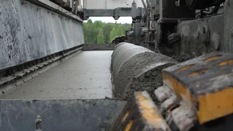 Side close-up view of road paving machine making screed, forest in background Stock Footage 158050379