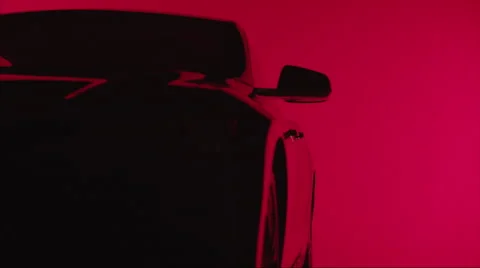 Side closeup angle on silhouette of a sleek car against sexy red background Stock Footage 64912840