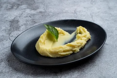 Side dish: mashed potato on black plate decorated with basil Stock Photos