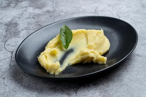 Side dish: mashed potato on black plate decorated with basil Stock Photos
